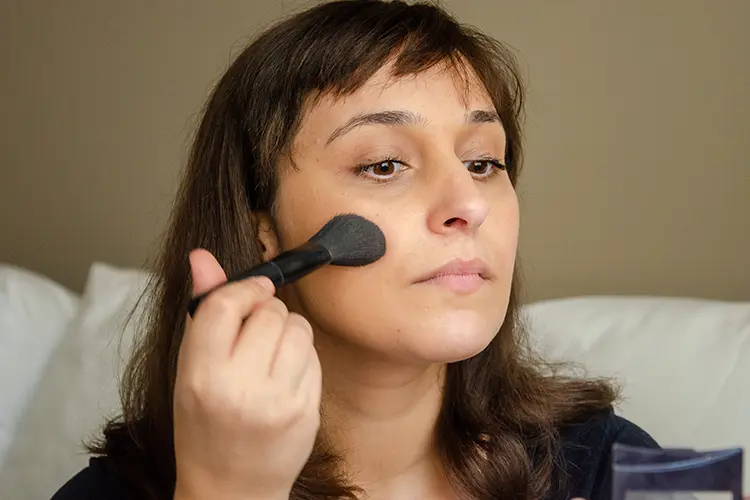 Woman applying foundation with brush natural light